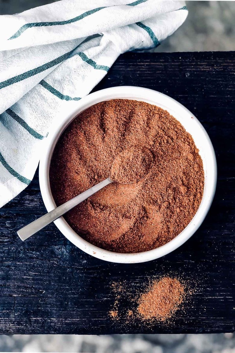 homemade ras el hanout spice blend in small bowl with spoon.