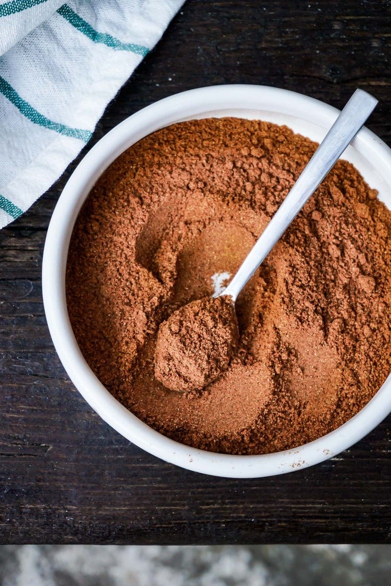 small bowl with homemade ras el hanout spice blend with spoon to scoop.