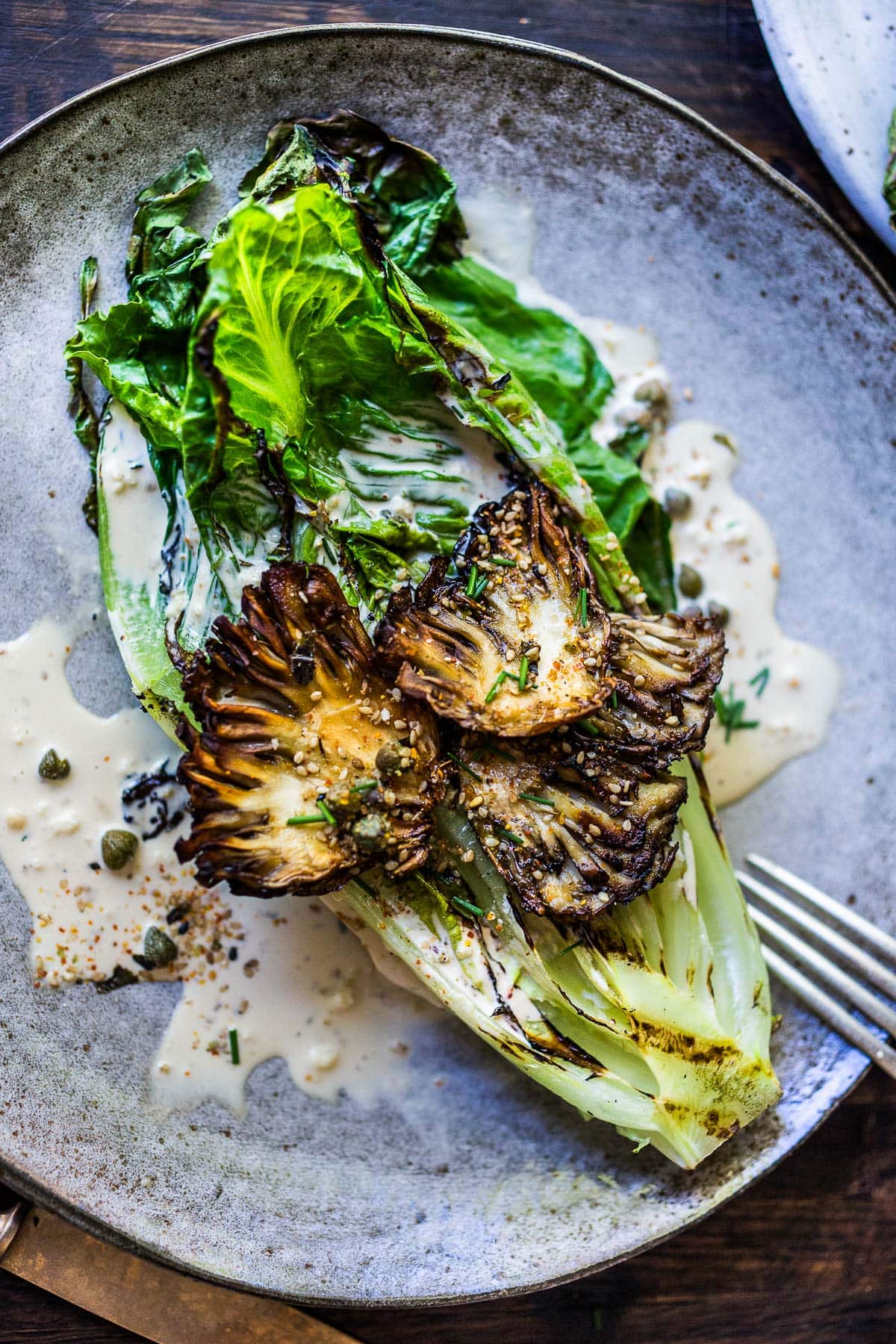 A Grilled Romaine Salad topped with Maitake Mushrooms, tossed in a Furikake Caesar dressing.