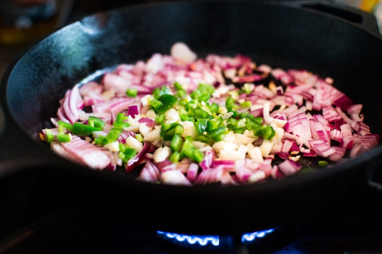 Crispy Jackfruit Carnitas - onions, garlic and jalapenos in a pan sauteing.