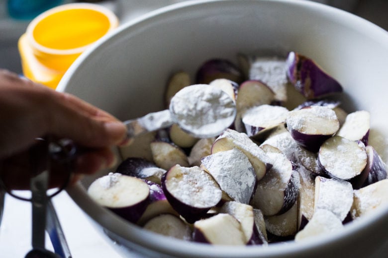 Coaating Chinese eggplant with cornstarch.