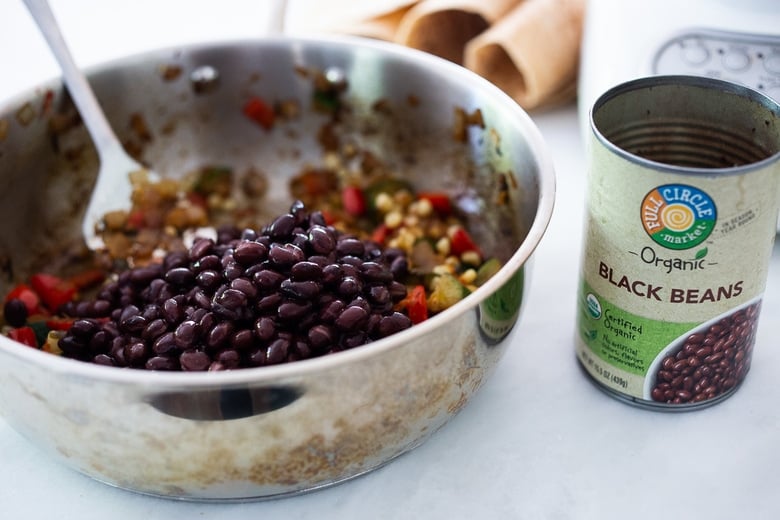 adding black beans to the enchilada filling.