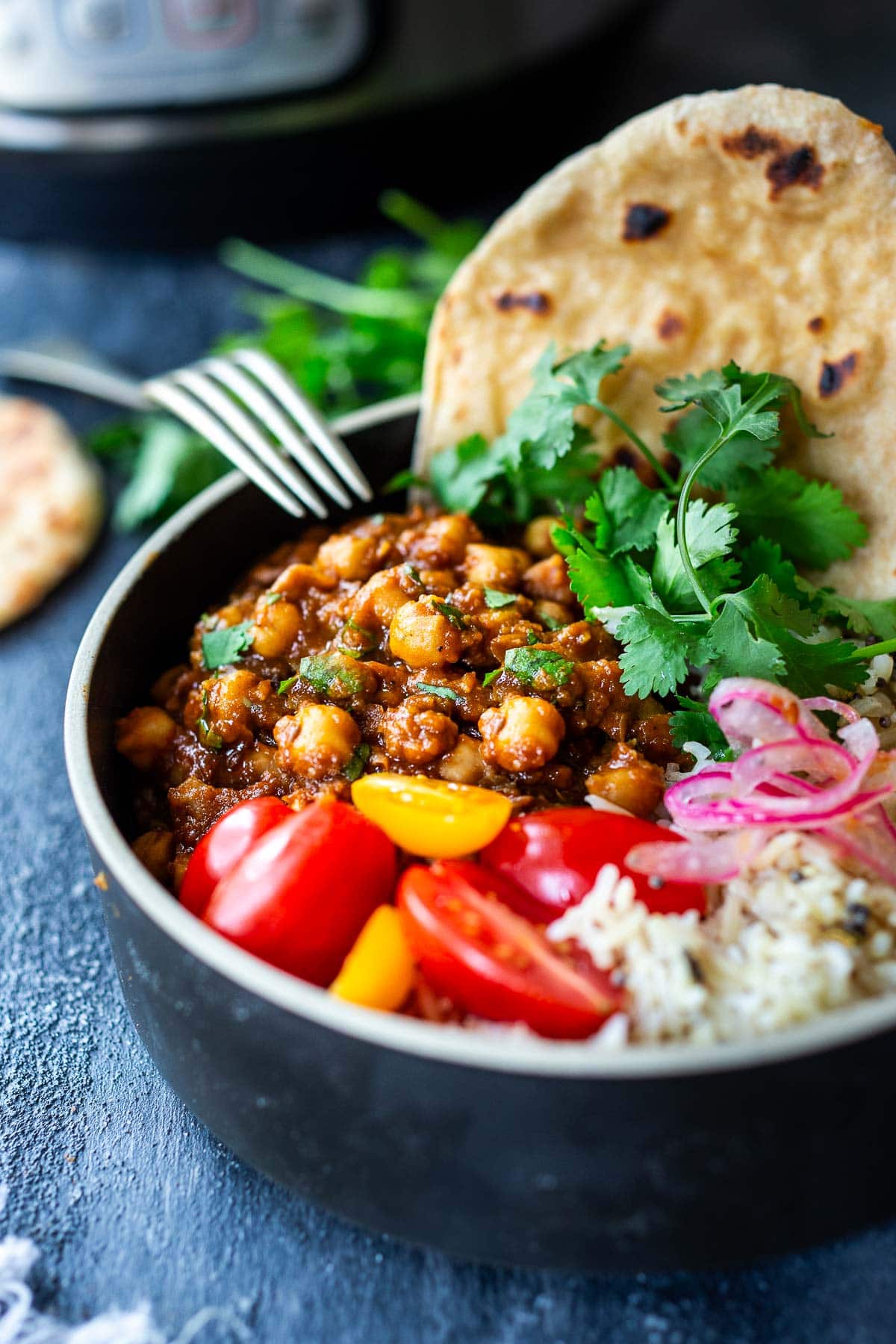 Chana masala in a bowl with rice and naan.
