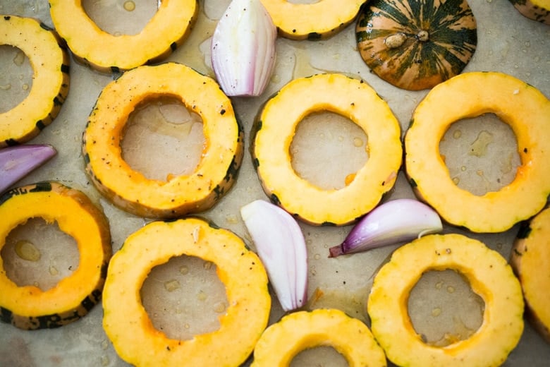 roasted delicata squash on a sheet pan in the oven 