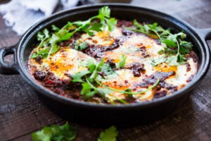 Moroccan Eggs! Eggs are baked in a flavorful lamb stew infused with Moroccan Spices, topped with Harissa Yogurt. A delicious breakfast or brunch recipe. #moroccanrecipes #bakedeggs #lambrecipes #groundlamb #brunch #breakfastrecipes