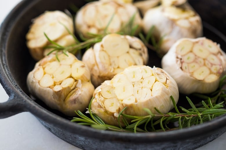 How to Roast Garlic in the oven (using whole heads of garlic or peeled garlic cloves). Roasting garlic transforms it! Spreadable, buttery, sweet, earthy, and complex it has a multitude of uses in the kitchen! And so many health benefits! Whole cloves can be stored in olive oil in the fridge for up to 10 days, or made into a paste, to add to soups, stews, sauces, dressings and mashes. #roastedgarlic #bakedgarlic #garlic #garlicbenefits #roastgarlic 