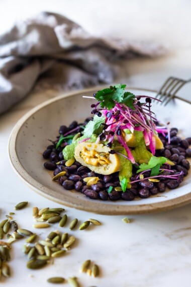 Butternut Tamales with flavorful Pumpkin Seed-Cilantro Sauce over a bed of seasoned black beans, topped with pickled onions and crunchy radishes! A flavorful vegetarian dinner. Vegan adaptable! Can be made ahead! #tamales #butternuttamales #vegantamales #vegetariandinner