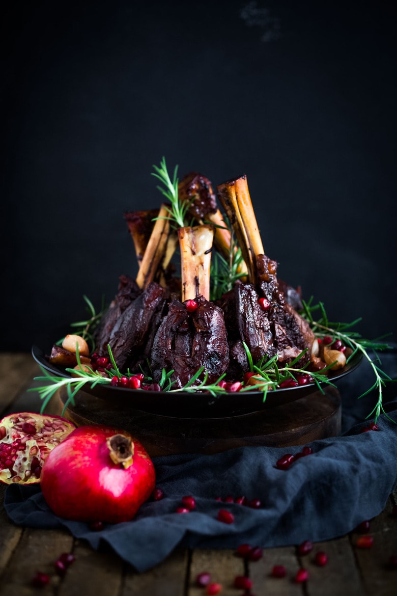 Oven Braised Lamb Shanks with Pomegranate - a festive, Moroccan-inspired lamb recipe that is elegant and delicious! Succulent lamb shanks are roasted in the oven until tender and falling off the bone. #lambshanks #moroccanlamb #braisedlamb #lambrecipes #bakedlamb #lambrecipes #lamb