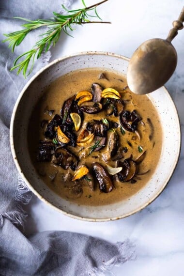 Creamy Mushroom Soup with Garlic chips and Rosemary - a delicious easy recipe that vegan and Keto adaptable and can be made in 30 minutes. Serve this for a special gathering or with crusty bread for quick and simple weeknight meal. #mushroomsoup #mushroomsouprecipe #mushroomrecipes #ketosoup