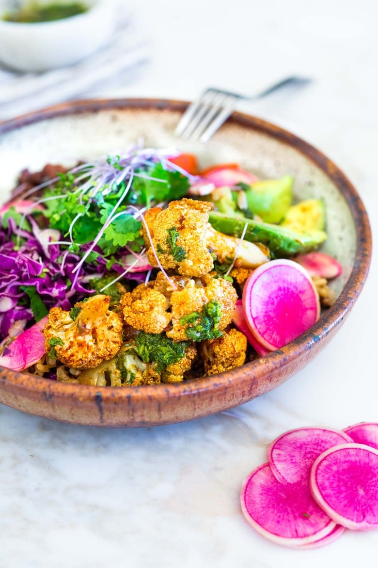 Smokey Cauliflower Chimichurri Bowls!  These filling vegan bowls are full of flavor and loaded up with healthy veggies. Served over seasoned black beans (and optional rice) with Mexican Slaw, radishes, avocado, cilantro and pickled onions. #roastedcauliflower #bowls #veganbowls #veganrecipes #buddhabowls #chimichurri #eatclean #cleaneating #plantbased #healthybowls