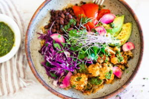 Smokey Cauliflower Chimichurri Bowls!  These filling vegan bowls are full of flavor and loaded up with healthy veggies. Served over seasoned black beans (and optional rice) with Mexican Slaw, radishes, avocado, cilantro and pickled onions. #roastedcauliflower #bowls #veganbowls #veganrecipes #buddhabowls #chimichurri #eatclean #cleaneating #plantbased #healthybowls