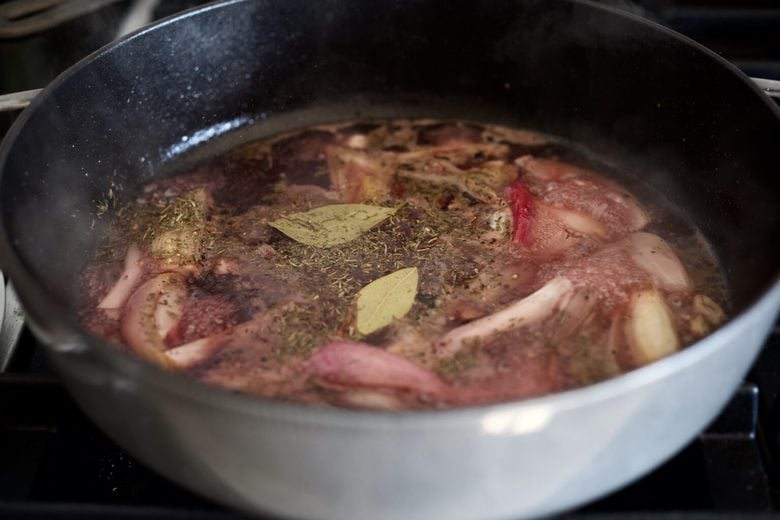 pan with wine, onions, garlic, bay leaves, and dried herbs to make braised cabbage.