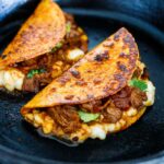 A simple authentic recipe for Birria Tacos, a flavorful Mexican beef or lamb stew that is spooned into tortillas with melty cheese, pickled onions, avocado and cilantro. Cook this in a ducth oven, slow cooker, or instant pot. 