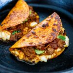 A simple authentic recipe for Birria Tacos, a flavorful Mexican beef or lamb stew that is spooned into tortillas with melty cheese, pickled onions, avocado and cilantro. Cook this in a ducth oven, slow cooker, or instant pot.