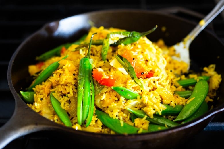 This fragrant, turmeric-infused, Indian Fried Rice is full of healthy veggies and can be made in under 30 minutes. Vegetarian, Gluten-free and Vegan adaptable, it is a fast and easy weeknight meal- great for using up leftover rice and veggies in the fridge. #turmericrice #veggierice #friedrice #vegandinner