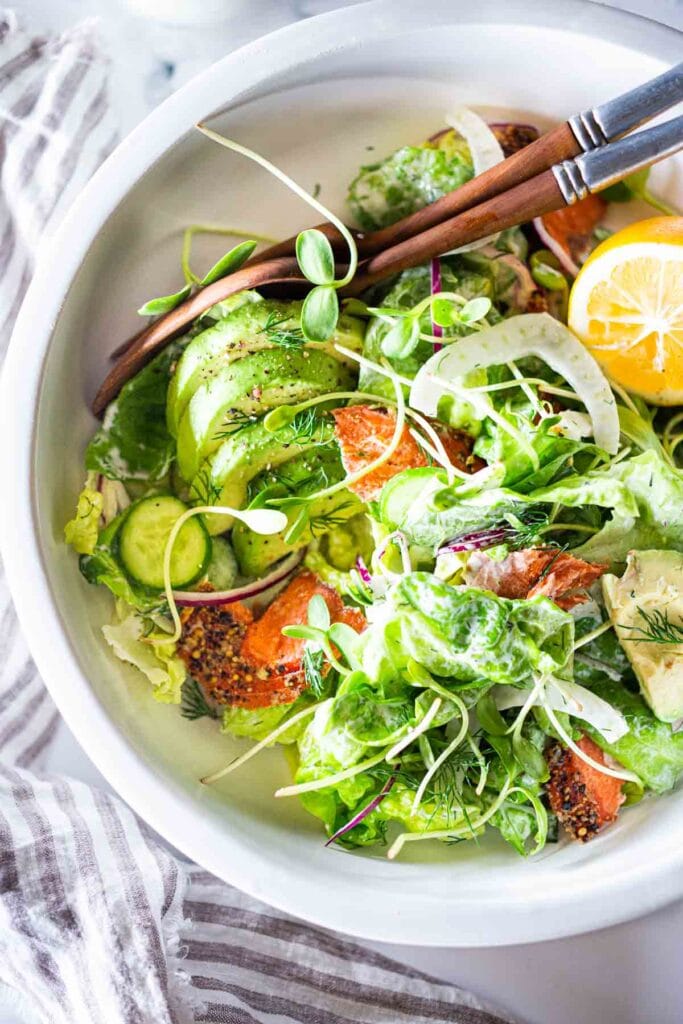 smoked salmon salad in a bowl with avocado, fennel, cucumber, herbs. 