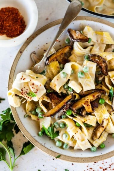 Vegan Alfredo for two, tossed in a delicious cashew (or hemp) cream, with sauteed mushrooms, Meyer lemon zest and a secret ingredient that gives this extra complexity and depth. Can be made in under 30 minutes! #veganalfredo #veganalfredosauce