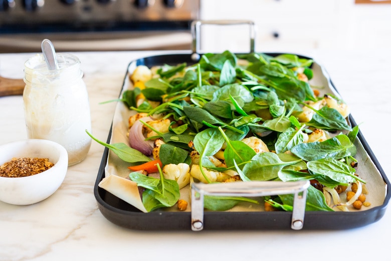 Warm Winter Salad - a hearty, Middle Eastern salad made on a sheet pan with roasted cauliflower, carrots, fennel and chickpeas, topped with wilting spinach, drizzled with Everyday Tahini Sauce and sprinkled with fresh dill and Dukkah. Vegan and Gluten-free. #sheetpandinner #warmsalad #vegansalad #sheetpanmeal #wintersalad #spinachsalad #cauliflowersalad #wintersalad #warmsalad 