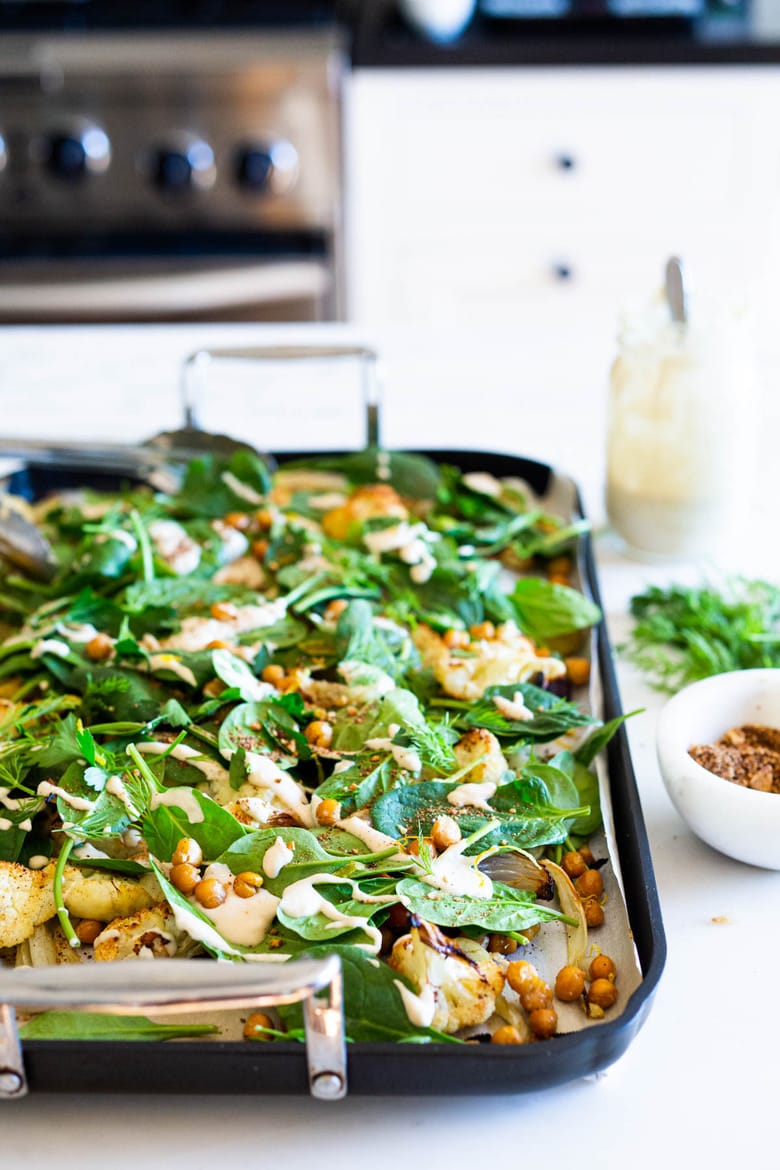 Warm Winter Salad - a hearty, Middle Eastern salad made on a sheet pan with roasted cauliflower, carrots, fennel and chickpeas, topped with wilting spinach, drizzled with Everyday Tahini Sauce and sprinkled with fresh dill and Dukkah. Vegan and Gluten-free. #sheetpandinner #warmsalad #vegansalad #sheetpanmeal #wintersalad #spinachsalad #cauliflowersalad #wintersalad #warmsalad 