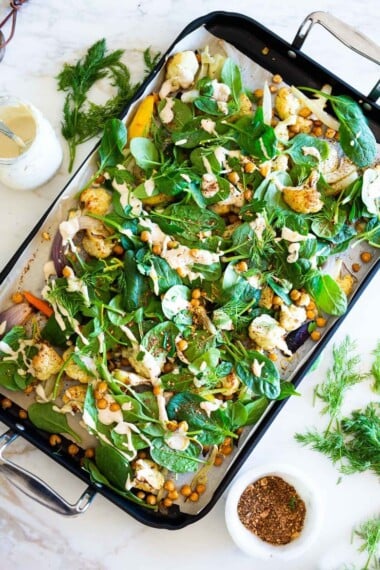 Warm Winter Salad - a hearty "entree" salad made on a sheet pan with roasted cauliflower, carrots, fennel and chickpeas, topped with wilting spinach, drizzled with Everyday Tahini Sauce and sprinkled with fresh dill and Egyptian Dukkah. Vegan and Gluten-free. #sheetpandinner #warmsalad #vegansalad #sheetpanmeal #wintersalad #spinachsalad #cauliflowersalad