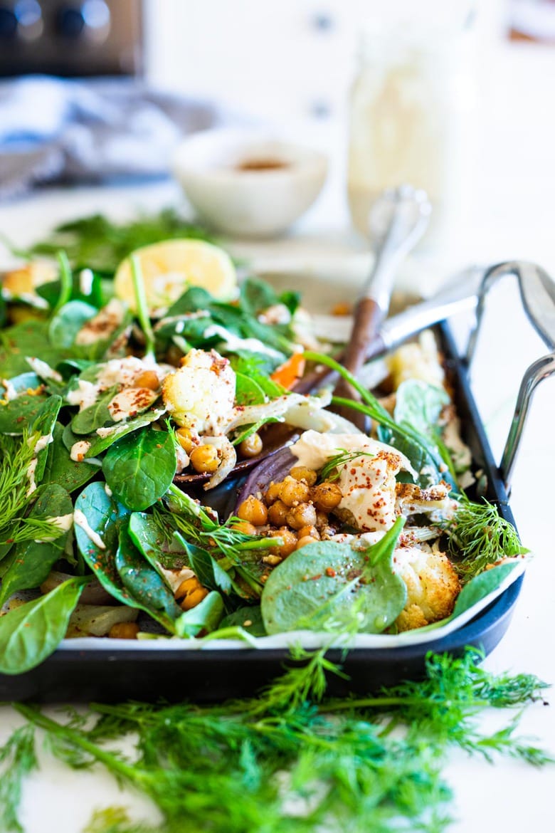 Warm Winter Salad - a hearty, Middle Eastern salad made on a sheet pan with roasted cauliflower, carrots, fennel and chickpeas, topped with wilting spinach, drizzled with Everyday Tahini Sauce and sprinkled with fresh dill and Dukkah. Vegan and Gluten-free. #sheetpandinner #warmsalad #vegansalad #sheetpanmeal #wintersalad #spinachsalad #cauliflowersalad #wintersalad #warmsalad 