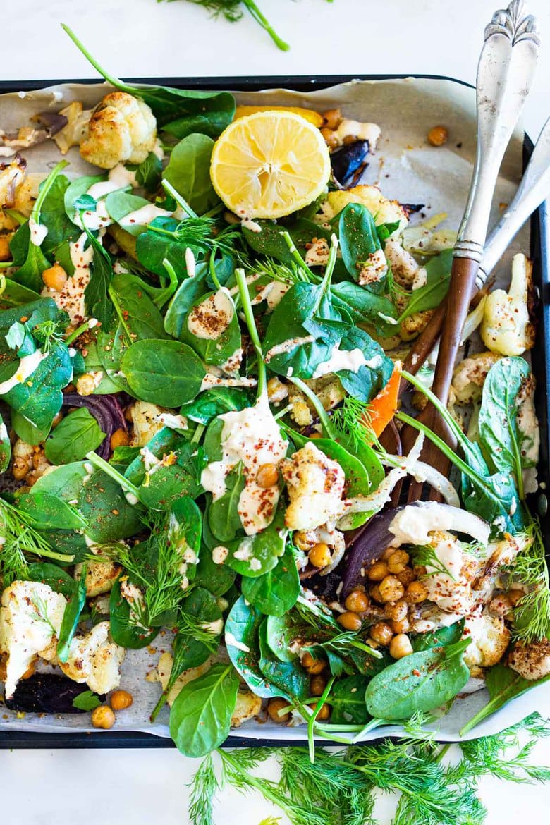 Warm Winter Salad - a hearty, Middle Eastern salad made on a sheet pan with roasted cauliflower, carrots, fennel and chickpeas, topped with wilting spinach, drizzled with Everyday Tahini Sauce and sprinkled with fresh dill and Dukkah. Vegan and Gluten-free. #sheetpandinner #warmsalad #vegansalad #sheetpanmeal #wintersalad #spinachsalad #cauliflowersalad #wintersalad #warmsalad 