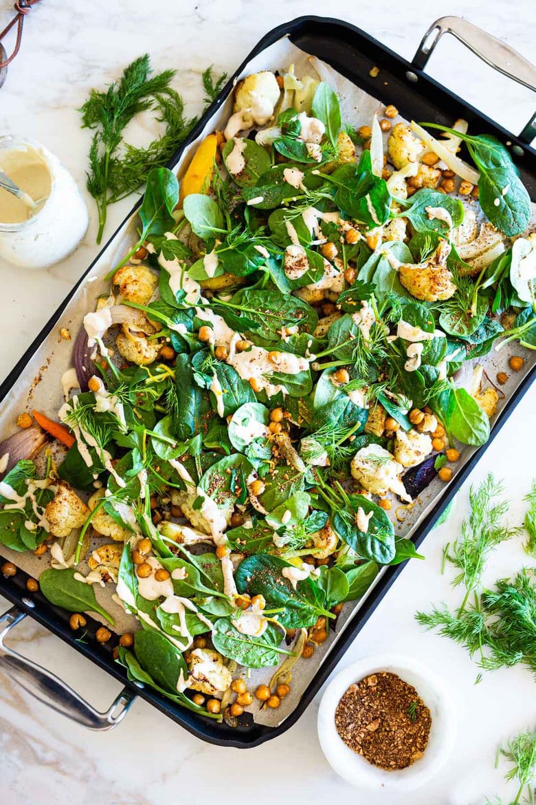Warm Winter Salad - a hearty, Middle Eastern salad made on a sheet pan with roasted cauliflower, carrots, fennel and chickpeas, topped with wilting spinach, drizzled with Everyday Tahini Sauce and sprinkled with fresh dill and Dukkah. Vegan and Gluten-free. #sheetpandinner #warmsalad #vegansalad #sheetpanmeal #wintersalad #spinachsalad #cauliflowersalad #wintersalad #warmsalad 