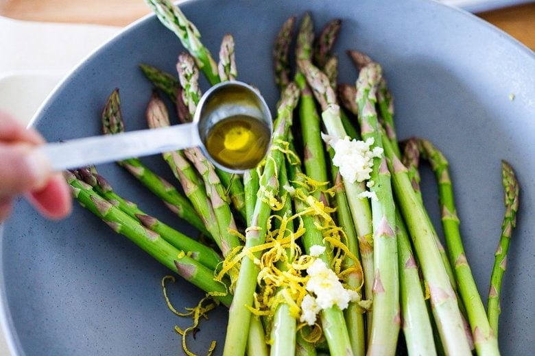 tossing asparagus with olive oil, salt and pepper, garlic and zest in a bowl.