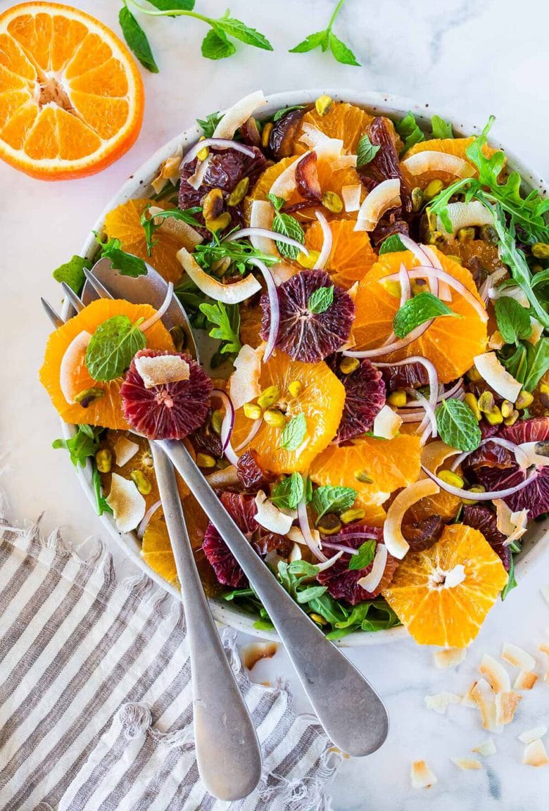 This Moroccan-inspired Citrus Salad with dates, arugula, mint, pistachios, and toasted coconut is dressed in the most flavorful Citrus Shallot Vinaigrette. It's deliciously juicy and vegan! #citrussalad #orangesalad