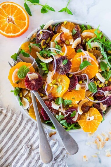 This Moroccan-inspired Citrus Salad with dates, arugula, mint, pistachios, and toasted coconut is dressed in the most flavorful Citrus Shallot Vinaigrette. It's deliciously juicy and vegan! #citrussalad #orangesalad