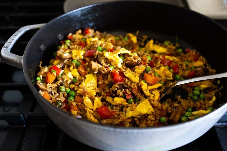 vegetarian Nasi Goreng (Indonesian Fried Rice) cooking in pan with colorful veggies and scrambled eggs.