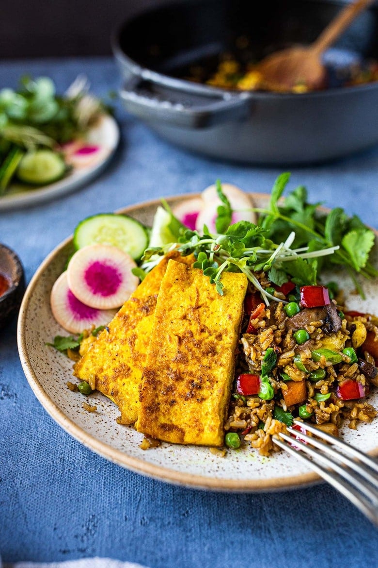 Vegetarian Nasi Goreng (Indonesian Fried Rice) loaded up with fresh veggies, served with crispy turmeric tofu and fresh herbs, sprouts, radish, cucumber.