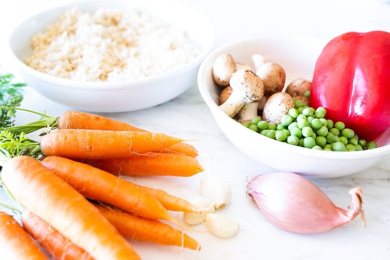 ingredients for nasi goreng (indonesian fried rice)- carrots, garlic, shallot, peas, mushrooms, red bell pepper, rice.