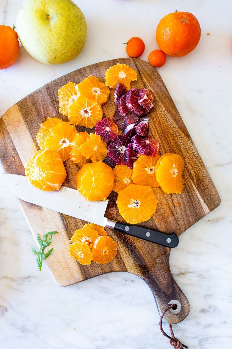 This Moroccan-inspired Citrus Salad with dates, arugula, mint, pistachios, and toasted coconut is dressed in the most flavorful Citrus Shallot Vinaigrette. It's deliciously juicy and vegan! #citrussalad #orangesalad 