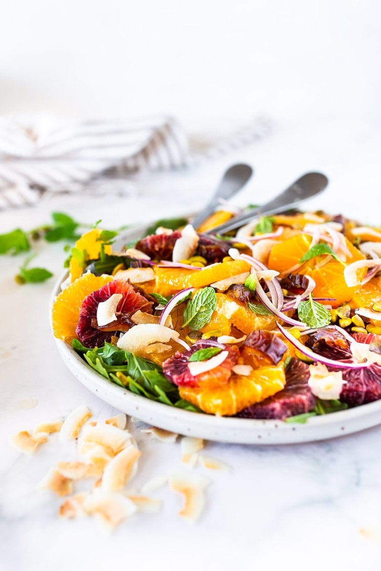 This Moroccan-inspired Citrus Salad with dates, arugula, mint, pistachios, and toasted coconut is dressed in the most flavorful Citrus Shallot Vinaigrette. It's deliciously juicy and vegan! #citrussalad #orangesalad 