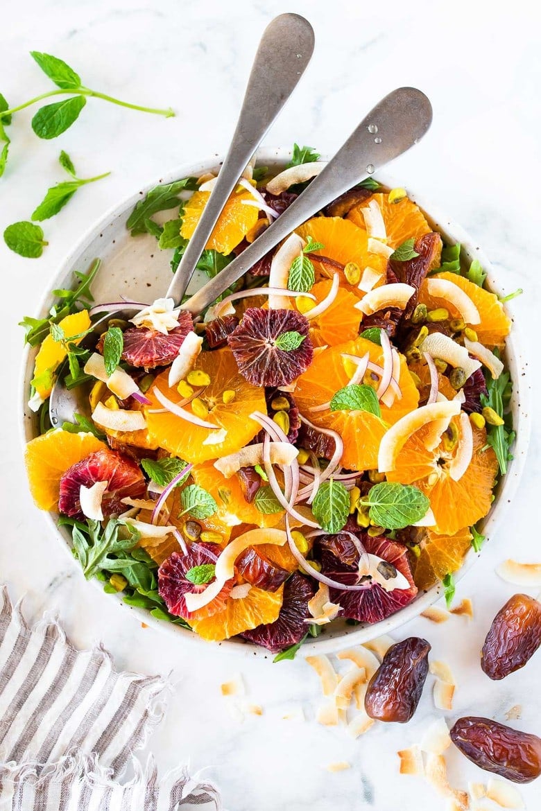 This Moroccan-inspired Orange Salad with dates, arugula, mint, pistachios, and toasted coconut is dressed in the most flavorful Citrus Shallot Vinaigrette. It's deliciously juicy and vegan! #citrussalad #orangesalad