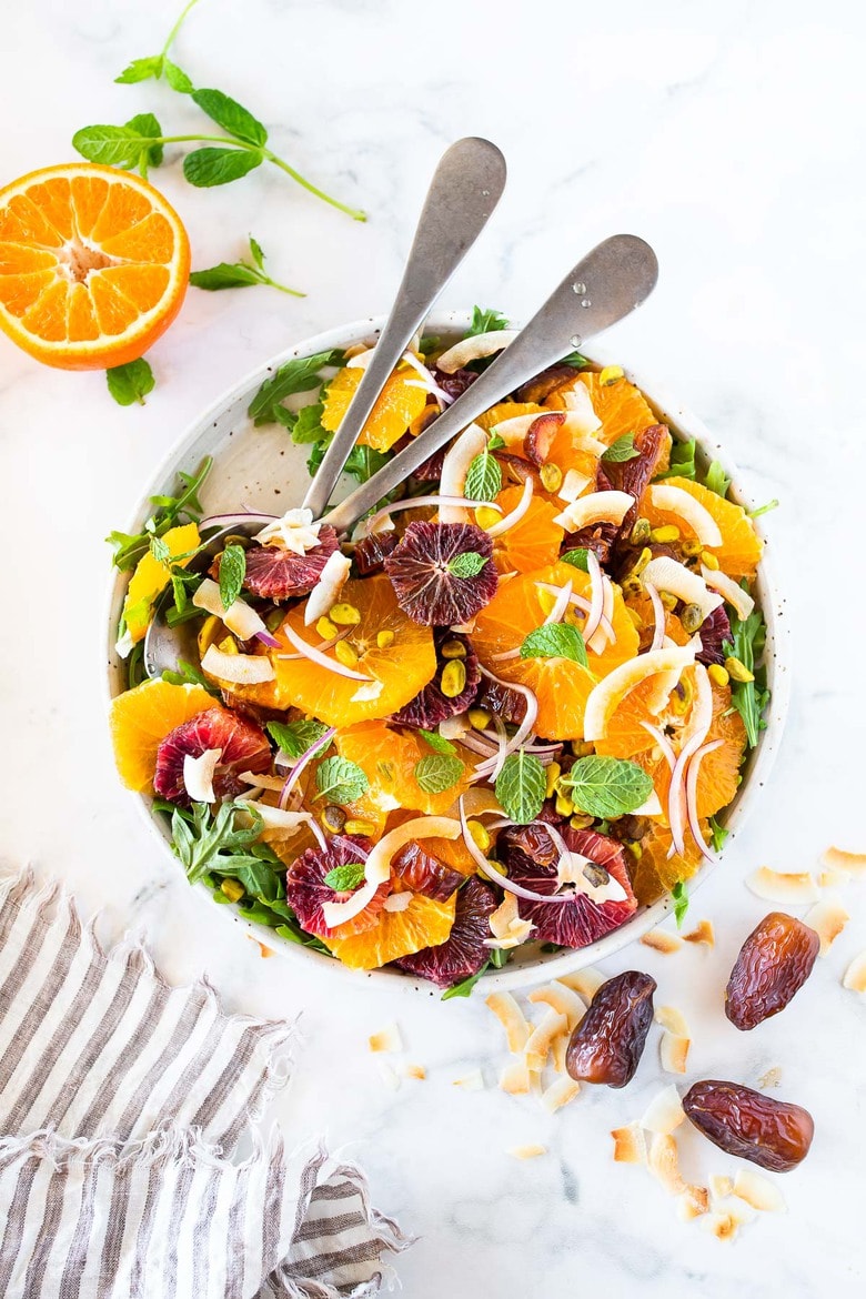 This Moroccan-inspired Citrus Salad with dates, arugula, mint, pistachios, and toasted coconut is dressed in the most flavorful Citrus Shallot Vinaigrette. It's deliciously juicy and vegan! #citrussalad #orangesalad 