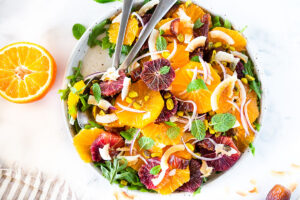 Citrus Salad with dates, arugula, mint, pistachios, and toasted coconut is dressed in the most flavorful Citrus Shallot Vinaigrette. It's deliciously juicy and vegan! #citrussalad #orangesalad