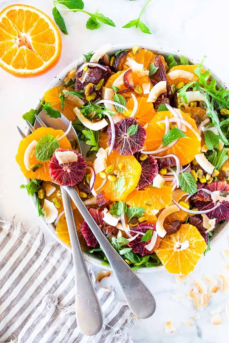 This Moroccan-inspired Citrus Salad with dates, arugula, mint, pistachios, and toasted coconut is dressed in the most flavorful Citrus Shallot Vinaigrette. It's deliciously juicy and vegan! #citrussalad #orangesalad