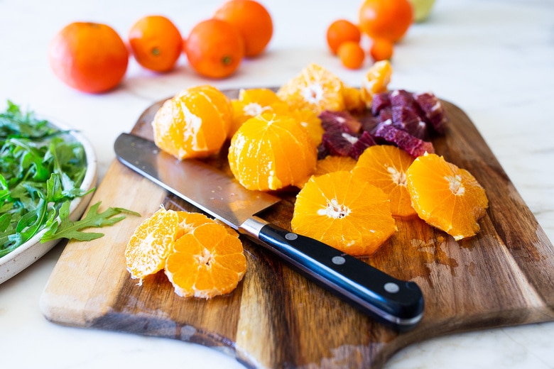 This Moroccan-inspired Orange Salad with dates, arugula, mint, pistachios, and toasted coconut is dressed in the most flavorful Citrus Shallot Vinaigrette. It's deliciously juicy and vegan! #citrussalad #orangesalad 