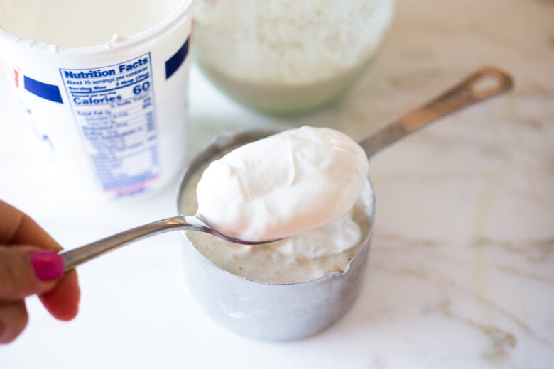 Adding sour cream to sourdough biscuit dough.