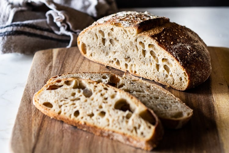 No-Knead Sourdough Bread sliced on a bread board