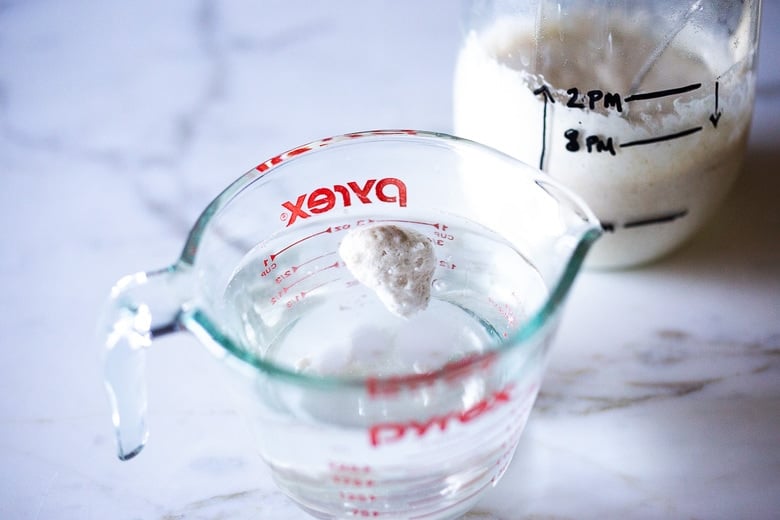 a tablespoon of sourdough starter floating in water for the float test