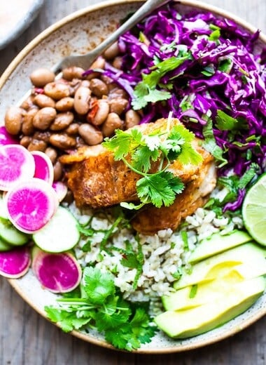 Crispy Baha Fish Taco Bowls made with beer-battered cod, cilantro rice, pinto beans, Mexican Slaw, avacodo and Baja Sauce!