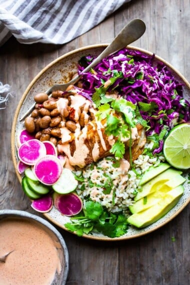 These Baja Fish Taco Bowls start with crispy beer-battered cod—the star of a classic Baja-style fish taco—then pile it over rice, beans, crunchy slaw, fresh veggies, and creamy chipotle sauce.