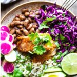 Baja Fish Taco Bowls made with beer-battered cod, Cilantro Lime Rice, Mexican Pinto Beans, Mexican Slaw, crunchy veggies, avocado and Chipotle Mayo! A tasty flavorful dinner! Vegan-adaptable. 