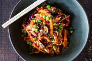 Here's a super tasty recipe for Vegan Kimchi Noodles, stir-fried with lots of healthy veggies you probably have on hand. Keep it vegan or add an egg, chicken or shrimp! Crispy tofu is also a delicious option here! #kimchi #kimchinoodles #kimchirecipes #vegannoodles