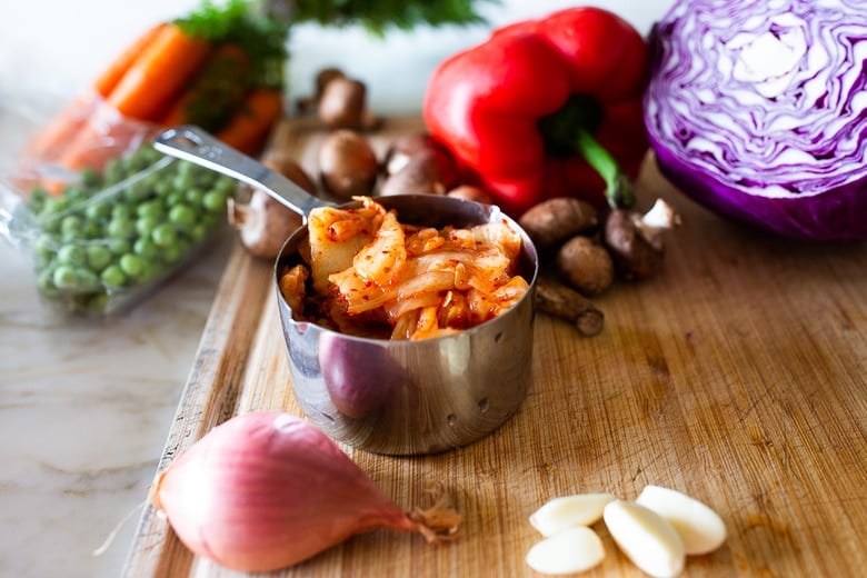 Here's a super tasty recipe for Vegan Kimchi Noodles, stir-fried with lots of healthy veggies you probably have on hand. Keep it vegan or add an egg, chicken or shrimp! Crispy tofu is also a delicious option here! #kimchi #kimchinoodles #kimchirecipes #vegannoodles