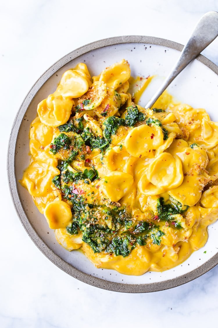 orecchiette with creamy carrot miso sauce served in bowl with carrot top gremolata and toasted breadcrumbs.