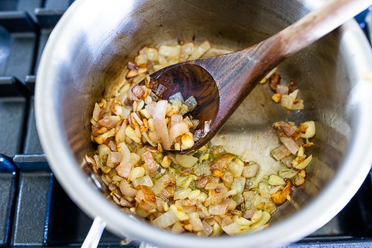 sautéed garlic and shallots in pot, stirred with wooden spoon.